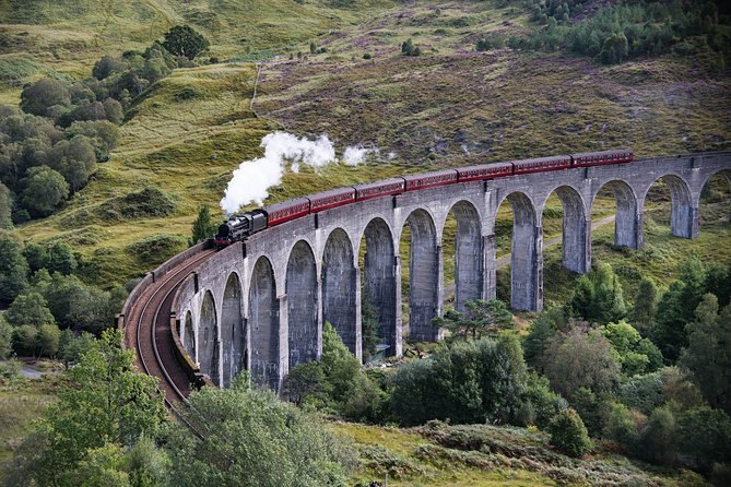 A steam train crossing the curving arches of the Glenfinnan Viaduct
