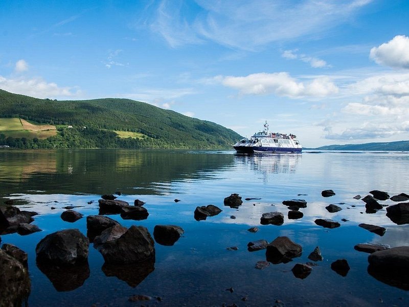 A Loch Ness cruise boat passing a rocky stretch of the loch shore