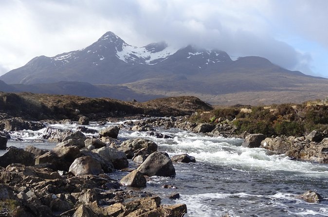 The river at Sligachan running over boulders below the snow-streaked Cuillin